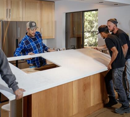 4 contractors placing a new countertop on a kitchen island